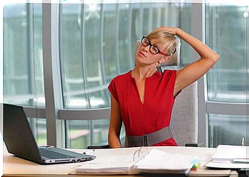 A woman stretching at work in front of her desk. 