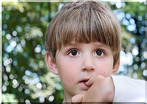 A child puts his fingers in his mouth.